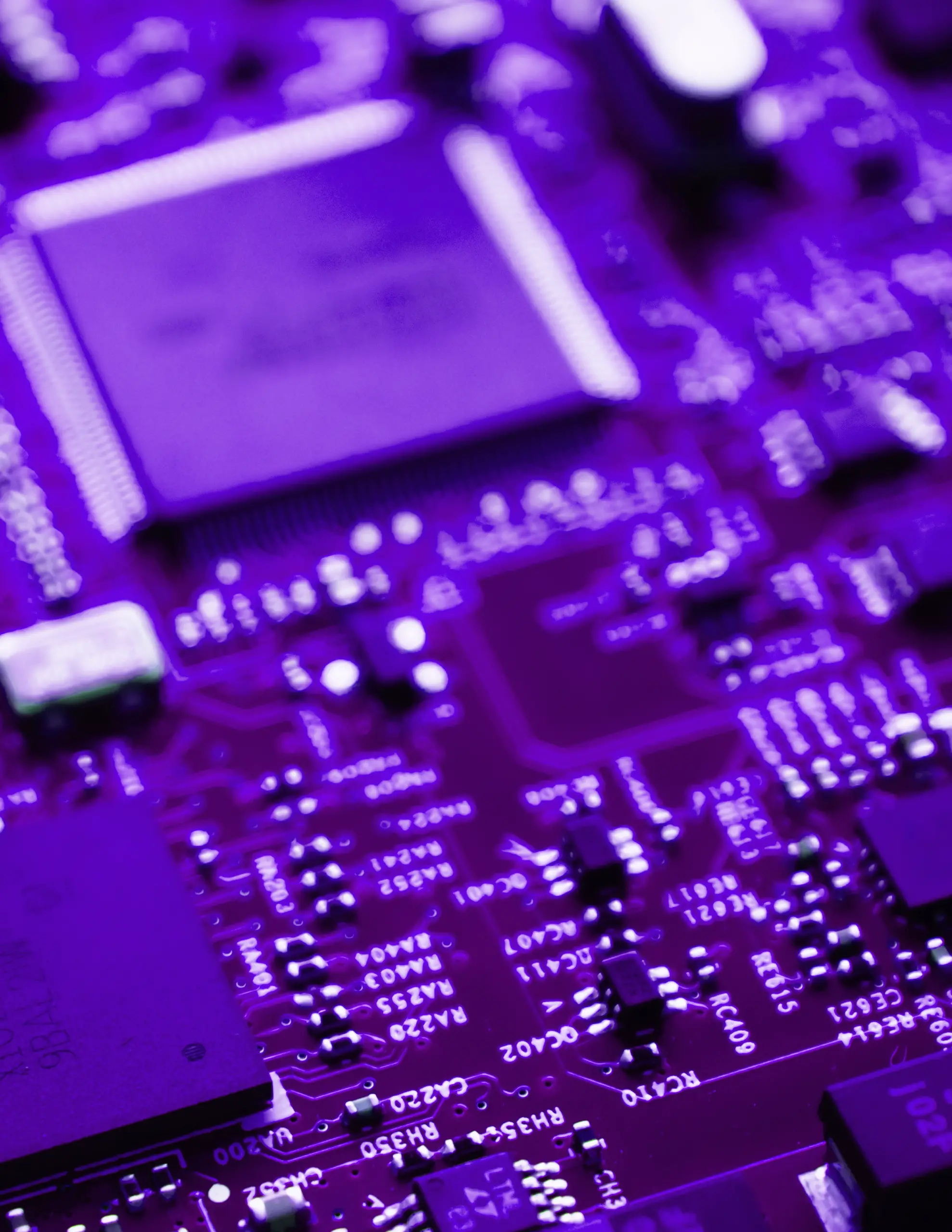Close-up image of a circuit board illuminated in purple, highlighting various electronic components and microchips.